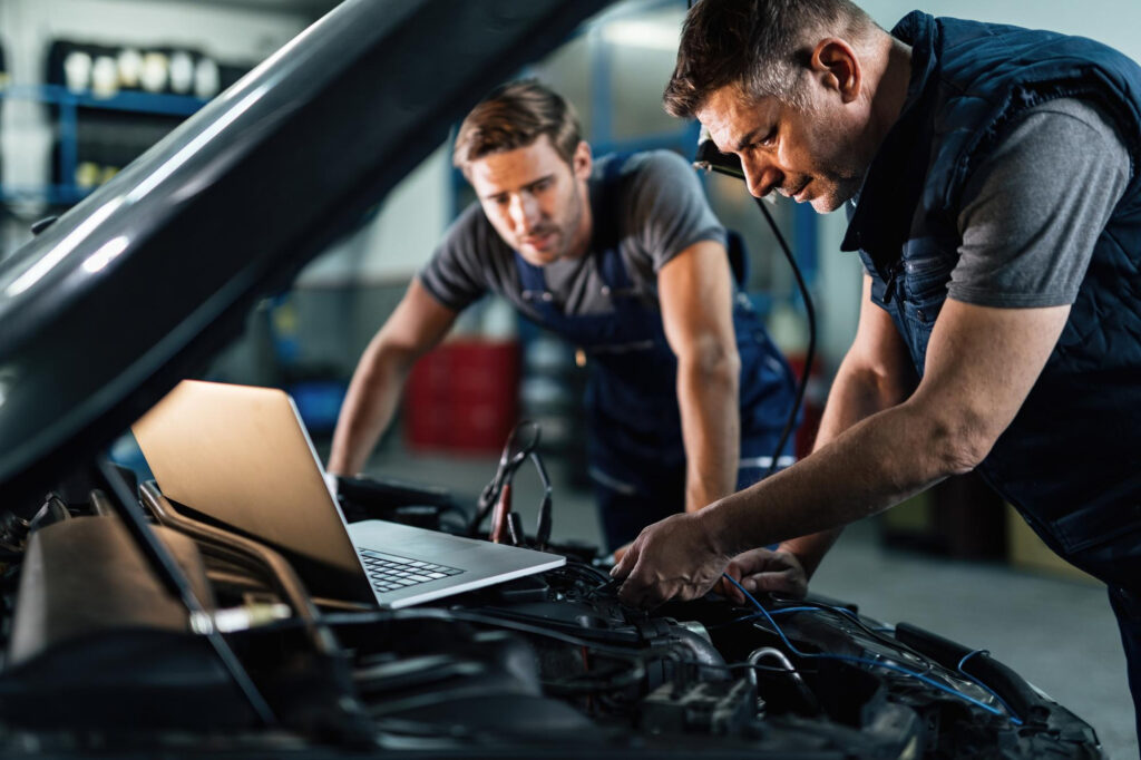 car-repairmen-using-laptop-while-doing-car-engine-diagnostic-auto-repair-shop